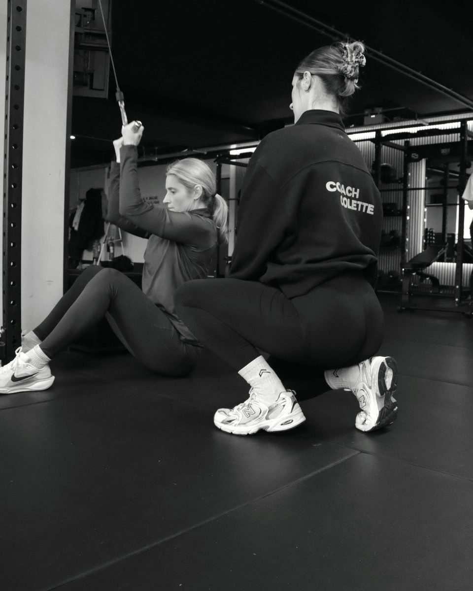 A qualified coach working with a client on the gym floor