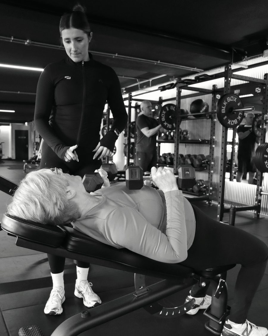 A PT Circle coach guiding a learner through a set on the gym floor in Reigate
